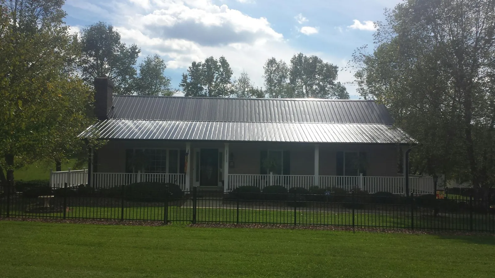 Gray metal roof on a brick ranch with a full width front porch — Gutter Guard Installation work by our crew in Ringwood
