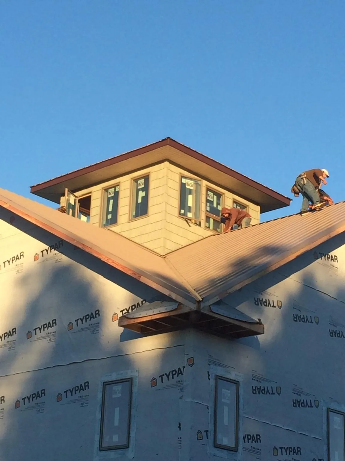 Roofers working around a rooftop cupola on a new metal roof at sunset — Roof Waterproofing in Ringwood by Roofing Brothers